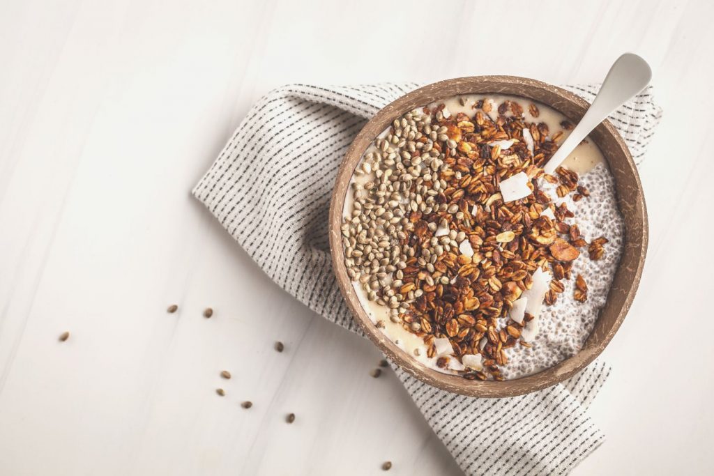 smoothie bowl with granola, chia pudding and hemp seeds in coconut shell bowl.