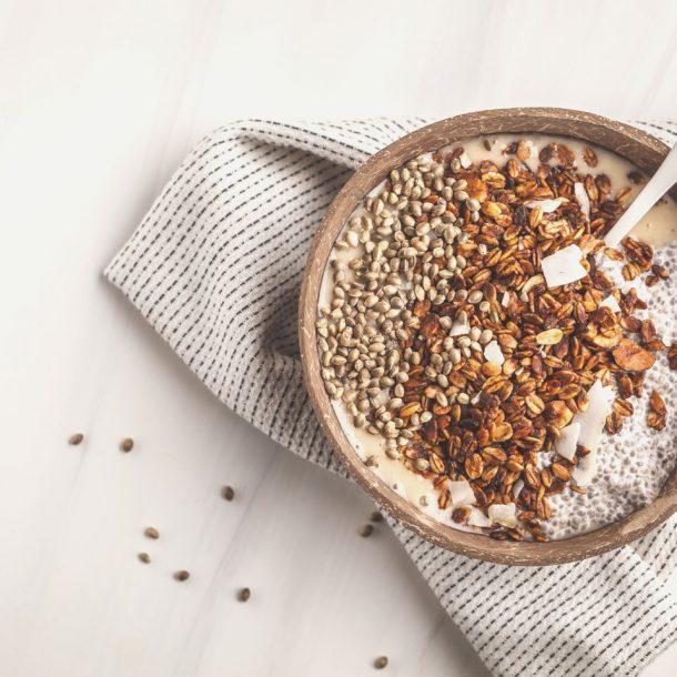 smoothie bowl with granola, chia pudding and hemp seeds in coconut shell bowl.
