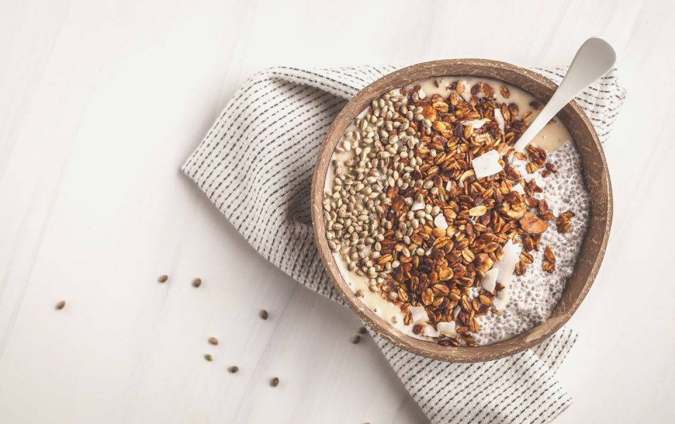 smoothie bowl with granola, chia pudding and hemp seeds in coconut shell bowl.