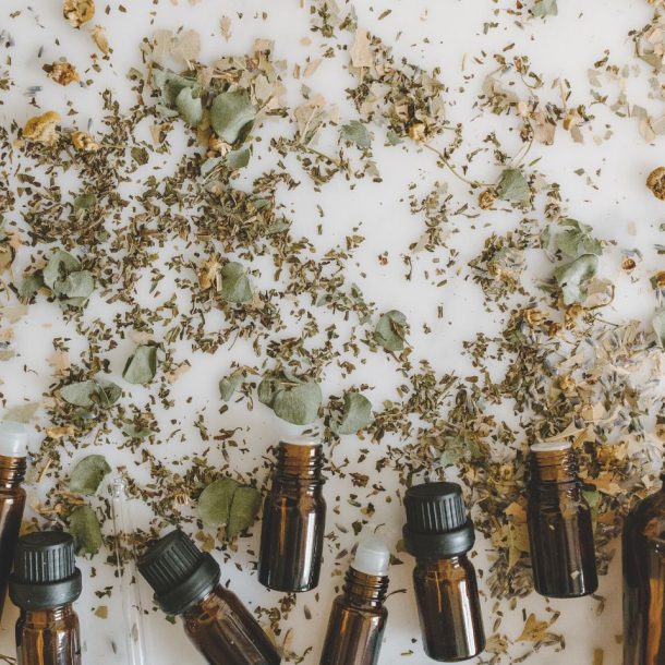 essential oil bottles and herbal medicine on white surface