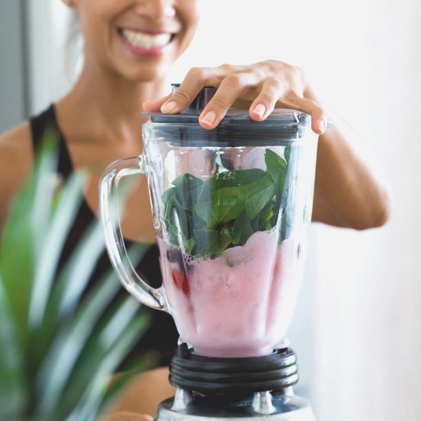 woman making a smoothie in a blender
