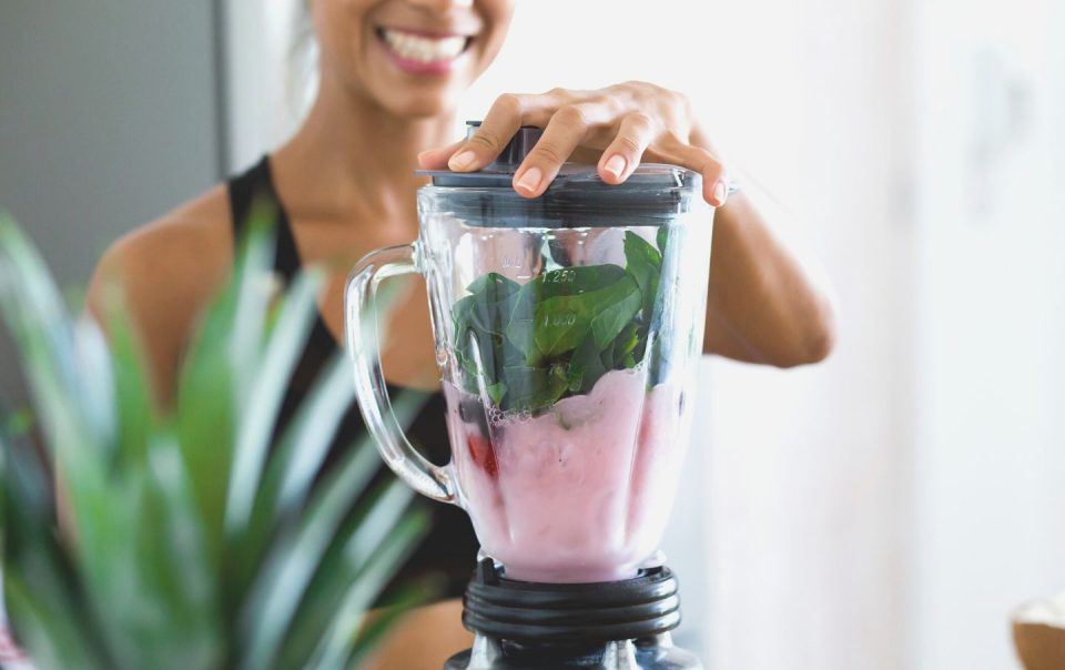 woman making a smoothie in a blender