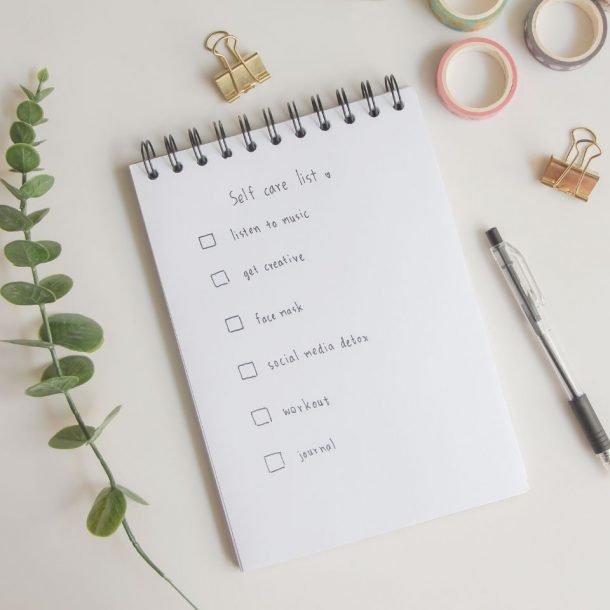 text list for self care on notebook with pen on white