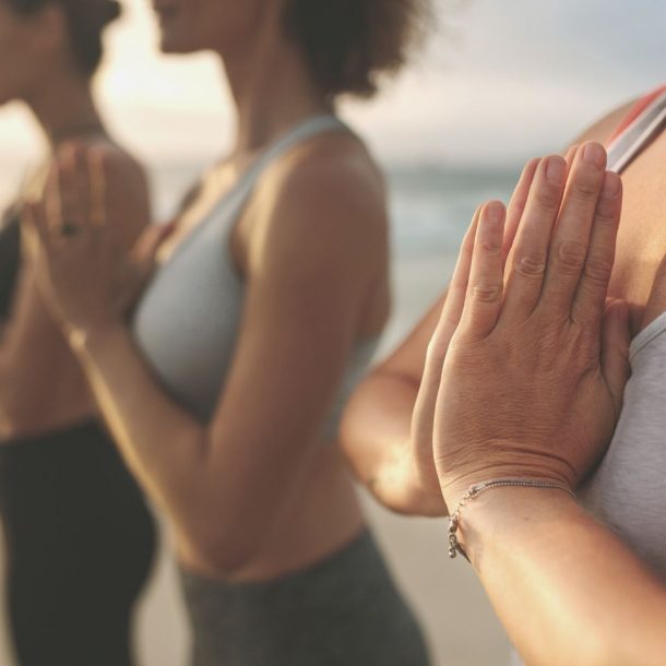fitness women practicing yoga standing at the beach
