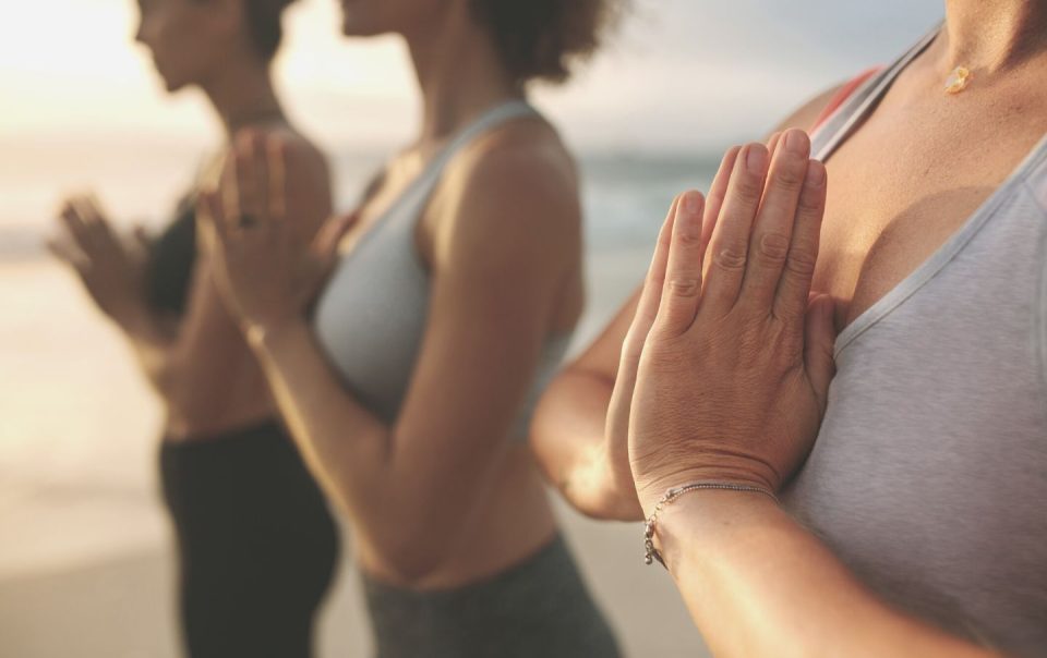 fitness women practicing yoga standing at the beach