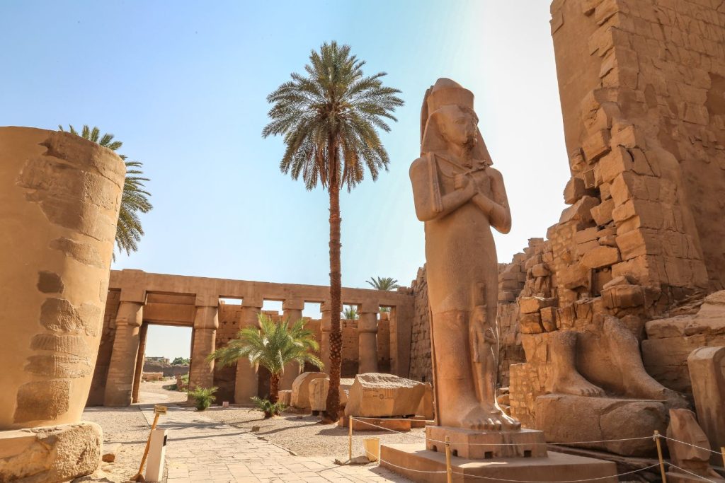 A majestic pharaoh statue stands in the heart of an ancient Egyptian temple.